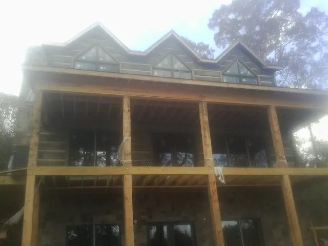 Dormers and porch framing on a large log home under construction — Roof Coating work by our crew in Danielsville