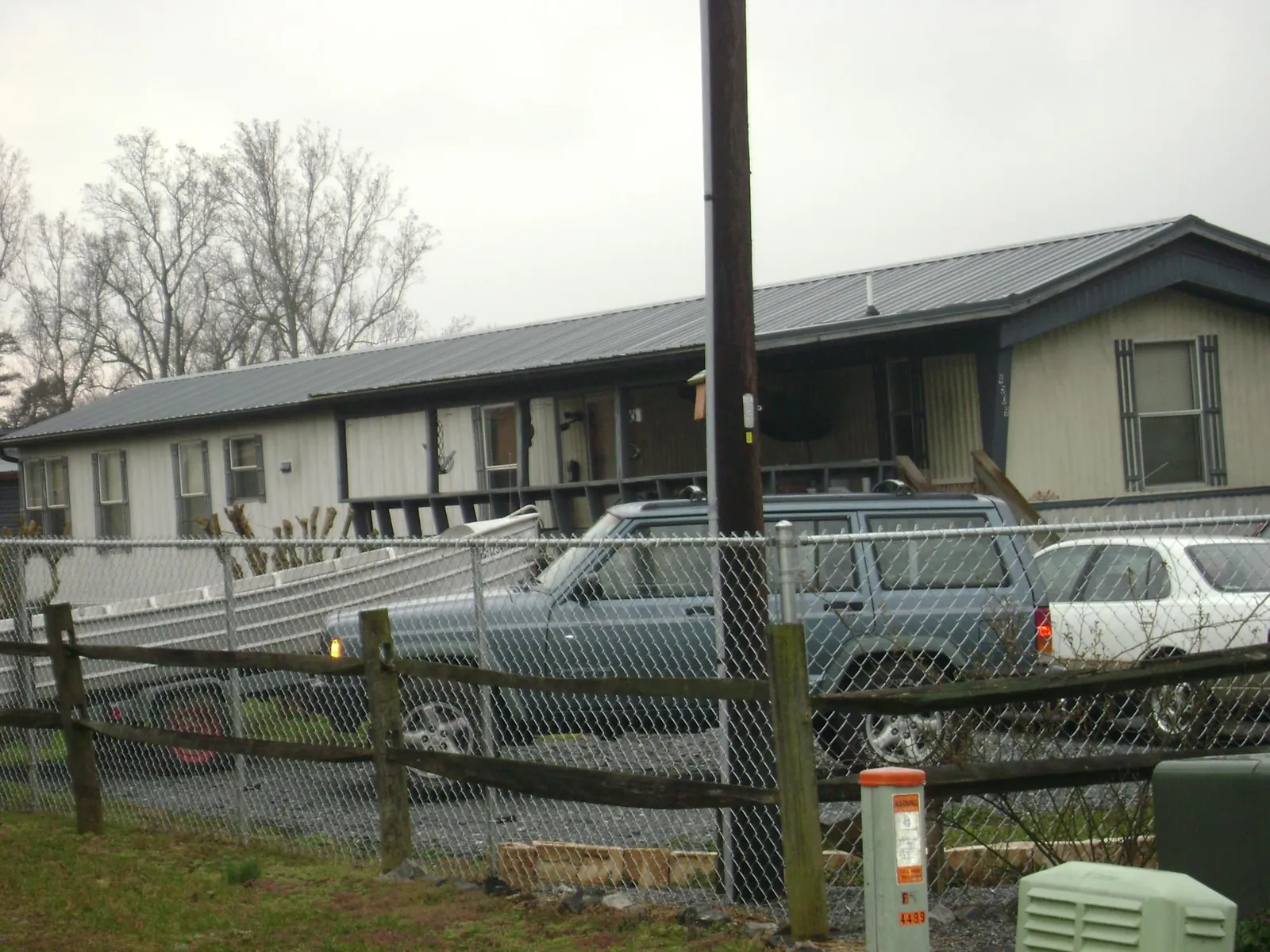 Dark metal roof on a long single story building behind a chain link fence in Danielsville
