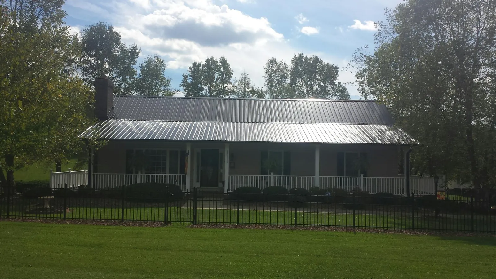 Gray metal roof on a brick ranch with a full width front porch — Gutter Guard Installation work by our crew in Danielsville